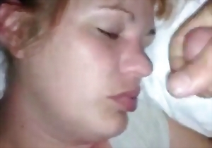 The sleeping lady is feeling his soft penis in front of her face